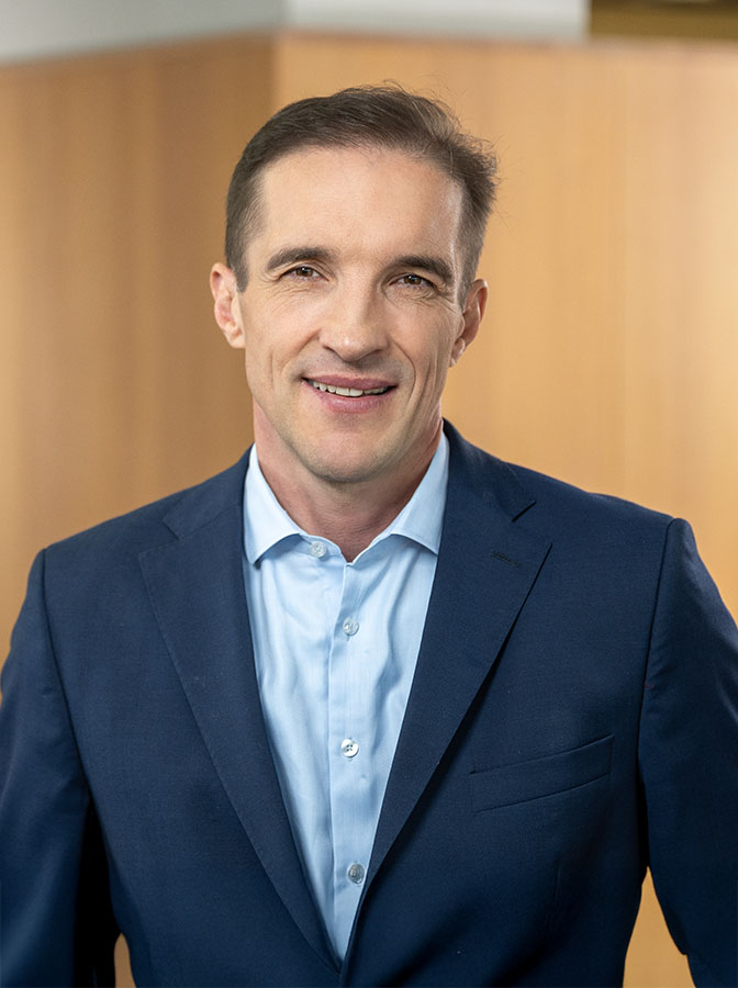 Portraitfoto eines Herren mit blauem Anzug ohne Krawatte