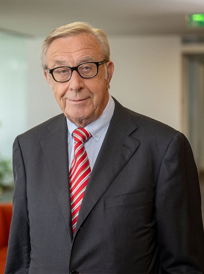 Portraitfoto eines älteren Herren mit dunkelgrauem Anzug und roter Krawatte