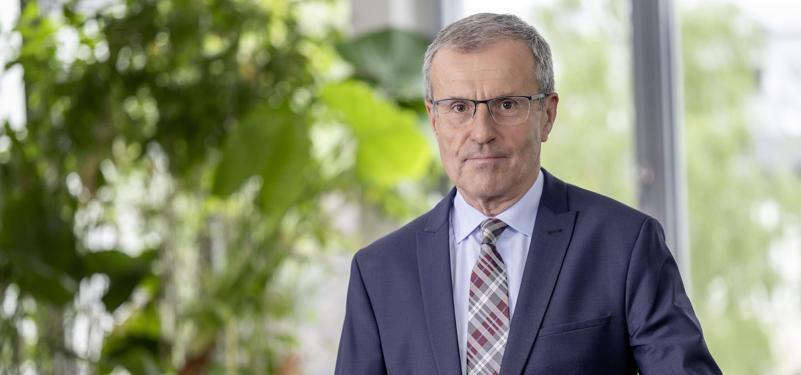 Portraitfoto eines Mannes mit Brille und blauem Anzug
