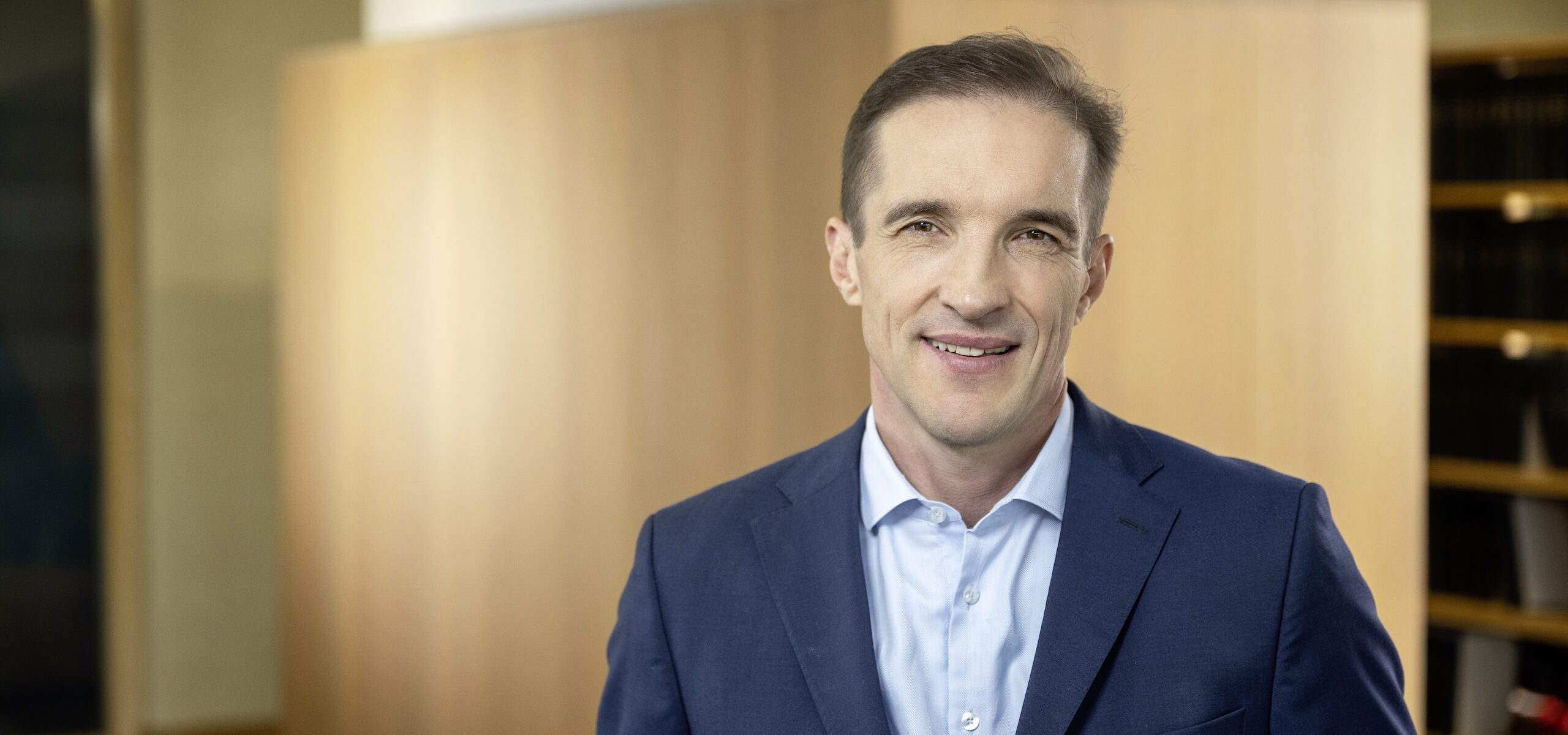 Portraitfoto eines Herren mit blauem Anzug ohne Krawatte