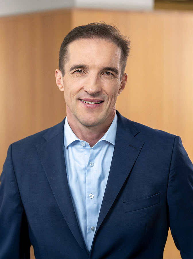 Portraitfoto eines Herren mit blauem Anzug ohne Krawatte