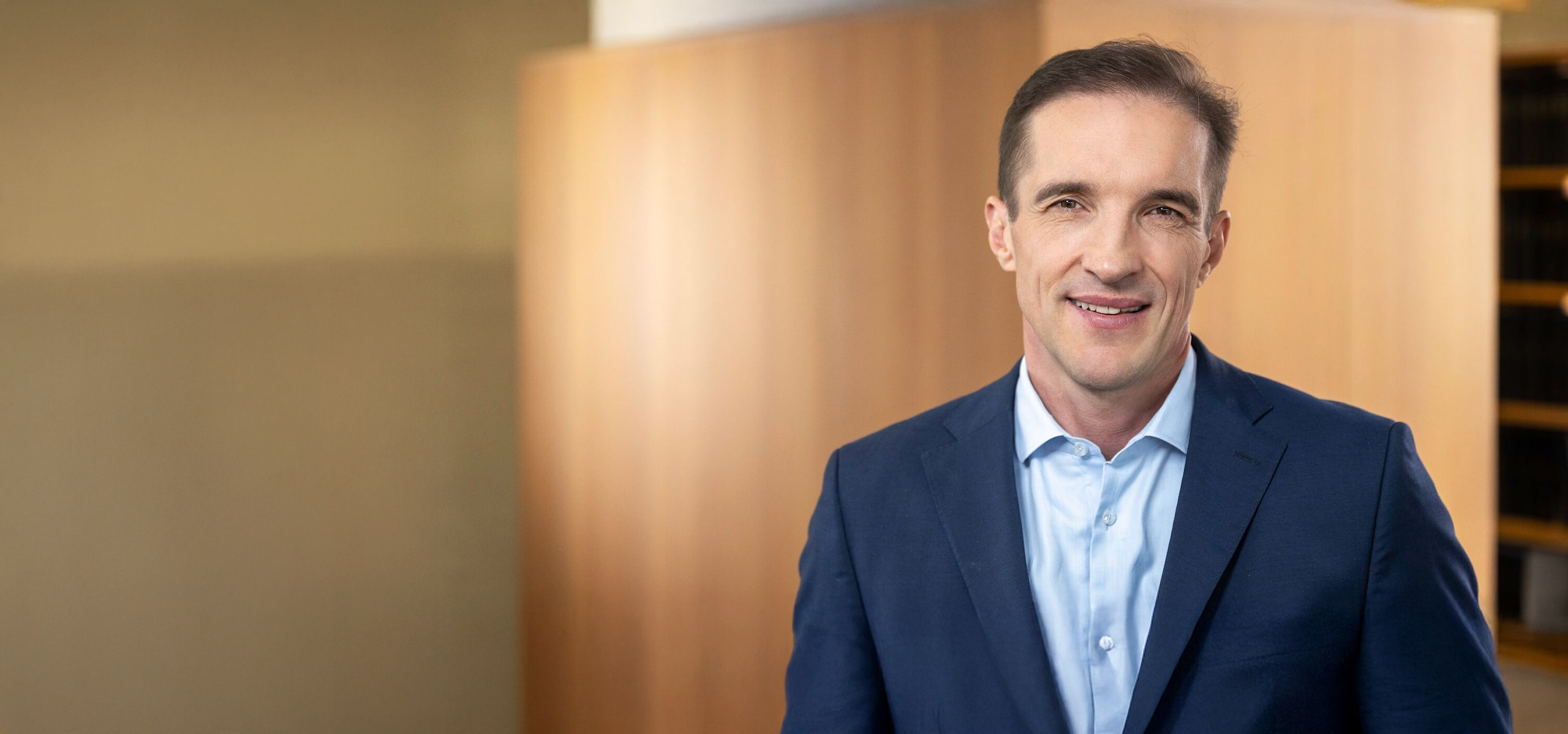 Portraitfoto eines Herren mit blauem Anzug ohne Krawatte