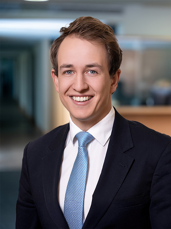 Portraitfoto eines Herren mit schwarzem Anzug und hellblauer Krawatte